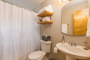 A bathroom with a toilet, a sink, a mirror, and a shower curtain.