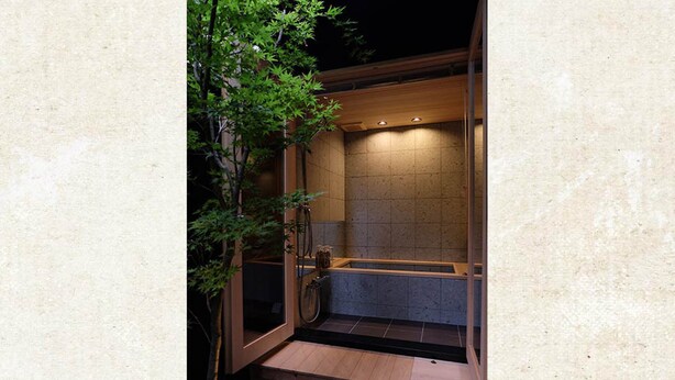 Un área pequeña y privada con jacuzzi al aire libre, un muelle de madera, una puerta de cristal y una pared de azulejos.