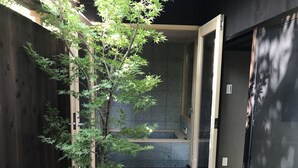 Un baño moderno con piso de baldosas negras, un banco de madera y un espejo grande.