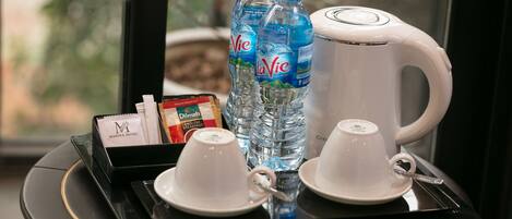 A tray with two white cups, two bottles of LaVie water, a white coffee maker, a box of English breakfast tea, and a package of Dilmah tea.