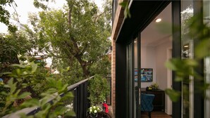 A balcony with a potted plant, a table with a vase and wine glasses, and a blue chair. - Marina Hotel (Hanoi)