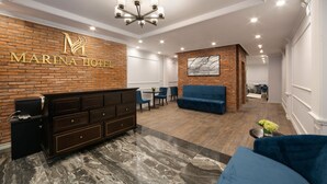 A modern lobby with a brick wall, a reception desk, a blue sofa, and a chandelier. - Marina Hotel (Hanoi)