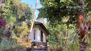 A stone staircase leading to a house with a tiled roof, surrounded by lush greenery and a stone wall. - Villa Sari Lombok, Hidden treasure (Lombok)