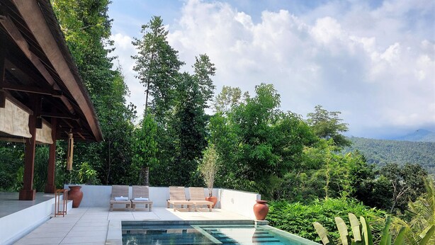 A swimming pool with lounge chairs and a pergola, surrounded by lush greenery and a mountainous backdrop. - Villa Sari Lombok, Hidden treasure (Lombok)