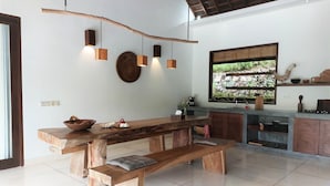 A modern kitchen with a large wooden table, built-in cabinets, and a stone backsplash. - Villa Sari Lombok, Hidden treasure (Lombok)