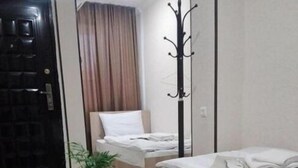 A hotel room with a bed, a small table with a wine glass, and a coat rack. - Hotel Petre Palace (Tbilisi)