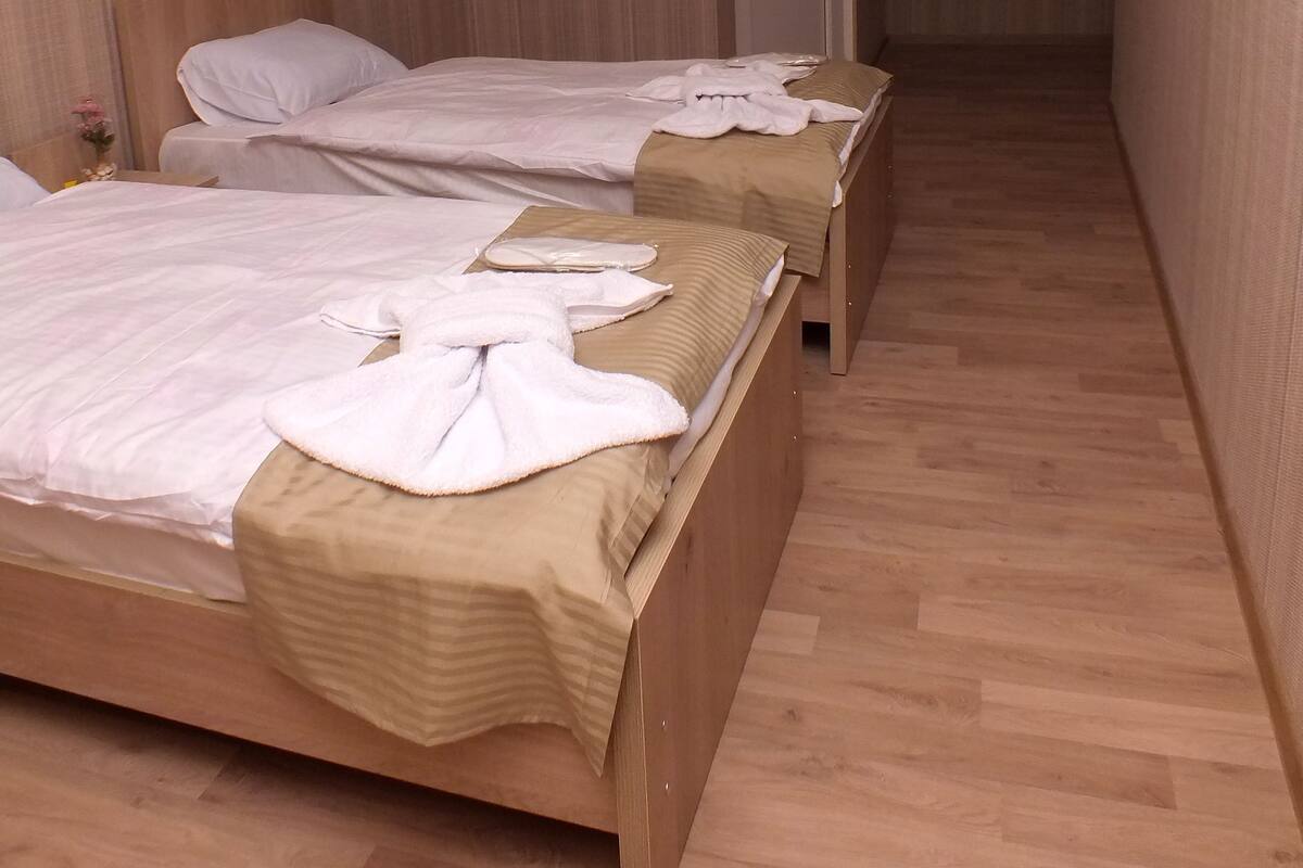 A hotel room with two wooden beds, a wooden floor, and a wooden wall panel.