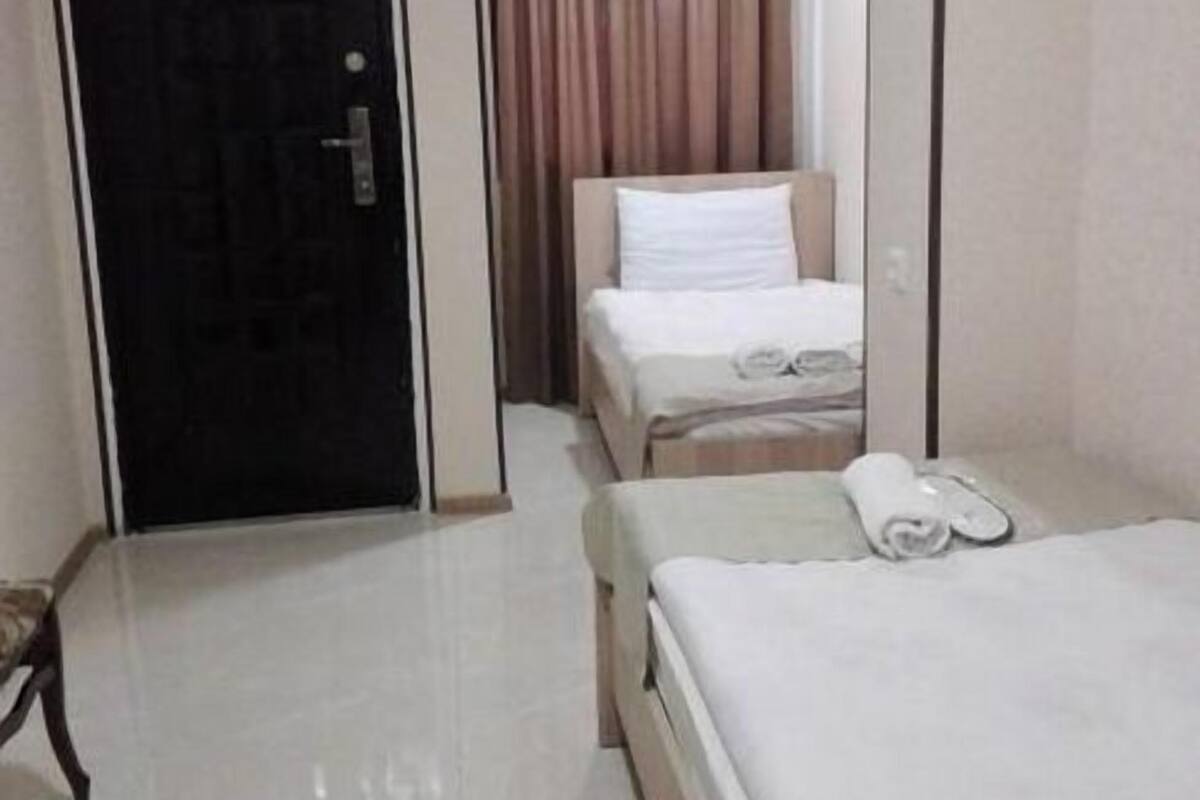 A hotel room with a bed, a chair, a desk, and a door.
