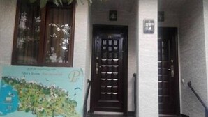A building with a staircase leading to an entrance, a door with a security camera, and a map on the wall. - Hotel Petre Palace (Tbilisi)