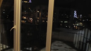 A balcony with a patterned floor and a view of a cityscape at night, including illuminated buildings and a tower. - Hotel Petre Palace (Tbilisi)