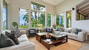 A spacious living room with large windows, a central coffee table, and multiple seating options.