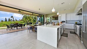 A modern kitchen with a large island, white cabinetry, and stainless steel appliances.