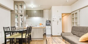 A compact kitchen with a dining area, a small refrigerator, and a sofa. - Comfortable DOTONBORI, OSAKACASTLE (Ōsaka-shi)