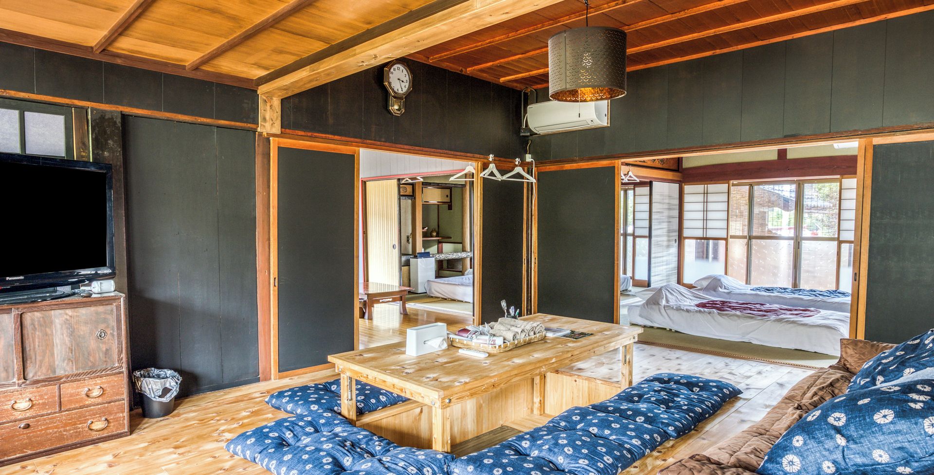 A traditional Japanese-style room with tatami flooring, a low wooden table, and a futon bed.