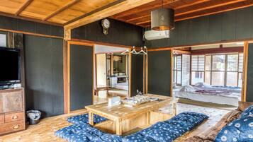 A traditional Japanese-style room with tatami flooring, a low wooden table, and a futon bed.
