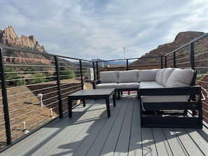 An outdoor deck with a sectional sofa and a table, overlooking a mountainous landscape. - 0.1 mile to Zion main gate. Canyon view rooftop deck. Kitchen, sleeps 6 (Springdale)