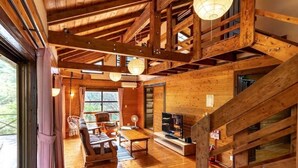 A spacious wooden cabin with a high ceiling, a fireplace, and a dining area.