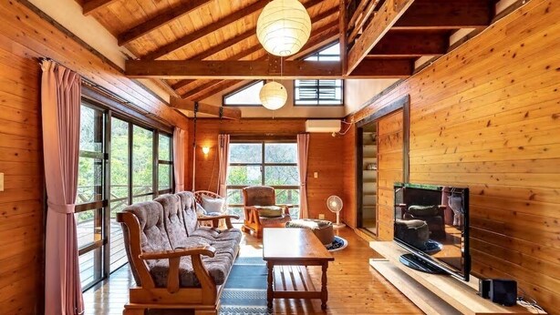 A cozy cabin interior with a wooden floor, a sofa, a table, and a television.