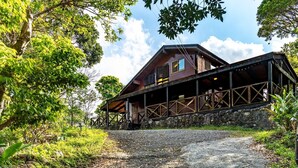 A rustic cabin with a stone foundation, wooden deck, and a covered porch.