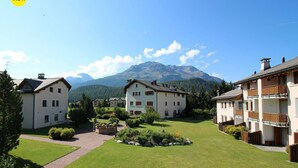 Un quartiere residenziale con diverse case a due piani, un prato curato e una montagna sullo sfondo.