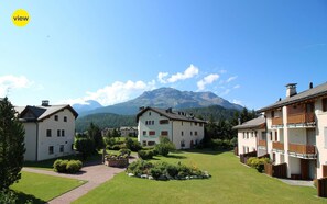A residential area with multiple two-story houses, a well-maintained lawn, and a mountain in the background.