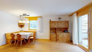 Una camera accogliente con un tavolo da pranzo in legno, sedie, un armadietto a muro in legno e una finestra vista alberi innevati.