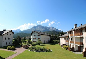 A residential area with multiple two-story houses, a well-maintained lawn, and a mountain in the background.
