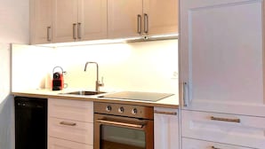 Een moderne keuken met roestvrijstalen apparatuur, een dubbele spoelbak en lichtkleurige keukenkastjes.