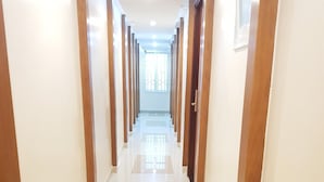 A long, well-lit hallway with tiled floors and wooden columns, leading to a bright room with a window. - Thanh An Hotel (Ho Chi Minh City)