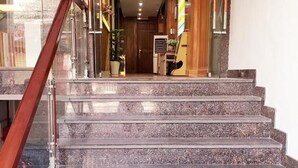 A staircase with a glass railing leading to a room with a bed and a desk. - Thanh An Hotel (Ho Chi Minh City)