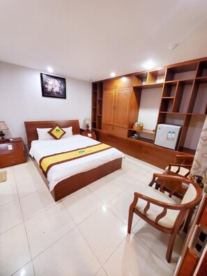 Une chambre d’hôtel avec un lit, une armoire en bois, un bureau et une chaise.