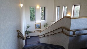 Un escalier muni de rampes, agrémenté de plantes en pot et de tableaux encadrés accrochés aux murs.