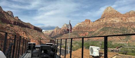 A deck with outdoor furniture overlooking a mountainous landscape.