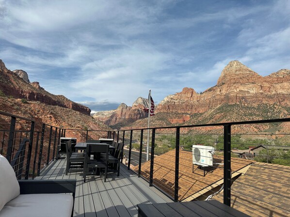 A deck with outdoor furniture overlooking a mountainous landscape.