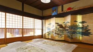 A traditional Japanese room with tatami flooring, shoji screens, and a sliding door with a landscape painting.