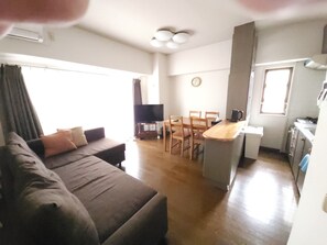 A compact living space with a sofa, a dining table, chairs, a kitchen area, and a television. - Convenient to Dotonbori,OsakaCastle (Ōsaka-shi)