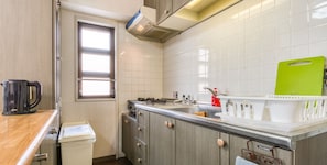 A compact kitchen with a window, a kettle, a sink, and a green cutting board. - Convenient to Dotonbori,OsakaCastle (Ōsaka-shi)
