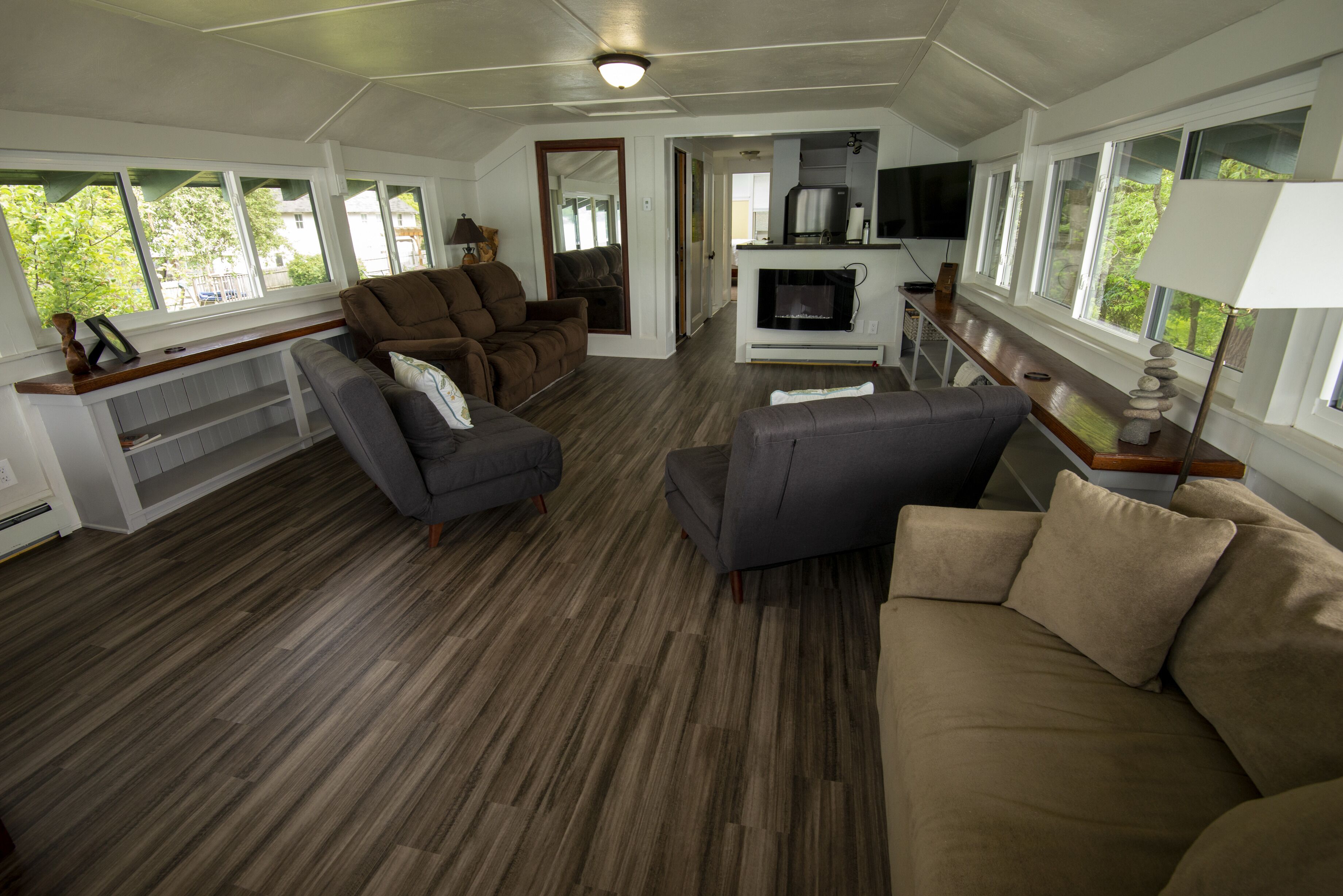 A spacious living area with a wooden floor, a sofa, a recliner, and a television.