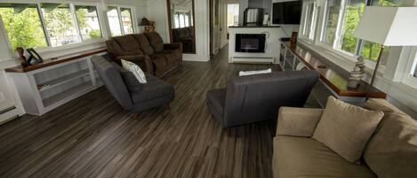 A spacious living area with a wooden floor, a sofa, a recliner, and a television.