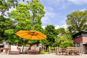 An outdoor seating area with wicker furniture and a large yellow umbrella.