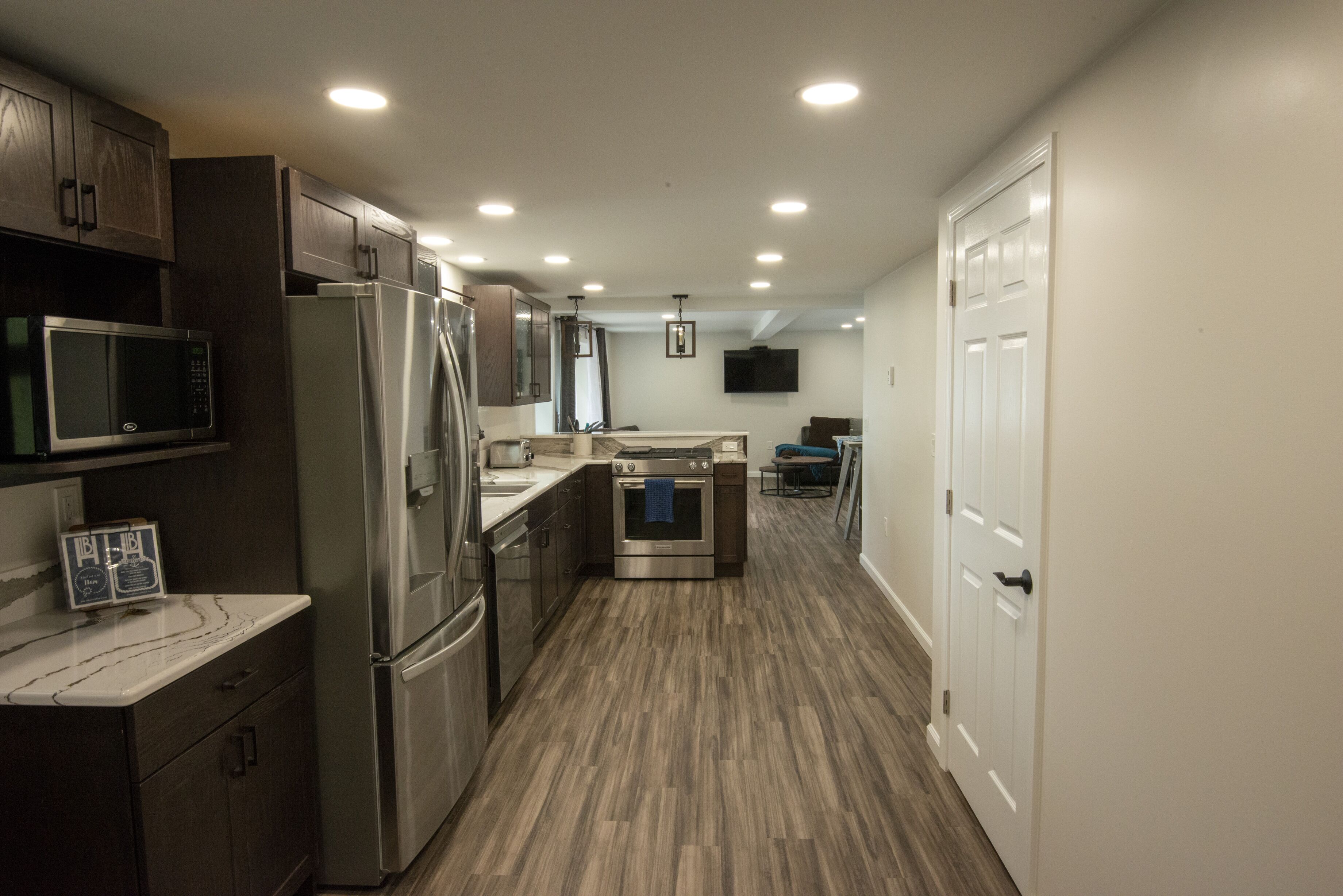 A modern kitchen with stainless steel appliances, wooden cabinets, and a marble countertop.
