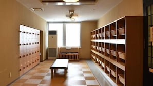 A hallway with lockers, a bench, and shelves with baskets. - Biei Shirogane Onsen Hotel Park Hills (Biei)