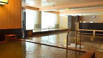 A large indoor swimming pool with a wooden floor, a glass railing, and a reception desk in the background.