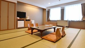 A hotel room with tatami flooring, a dining table with cushions, a television, and a kitchenette. - Biei Shirogane Onsen Hotel Park Hills (Biei)
