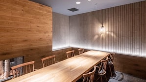 A conference room with a long wooden table, chairs, and a slanted ceiling with recessed lighting. - Biei Shirogane Onsen Hotel Park Hills (Biei)