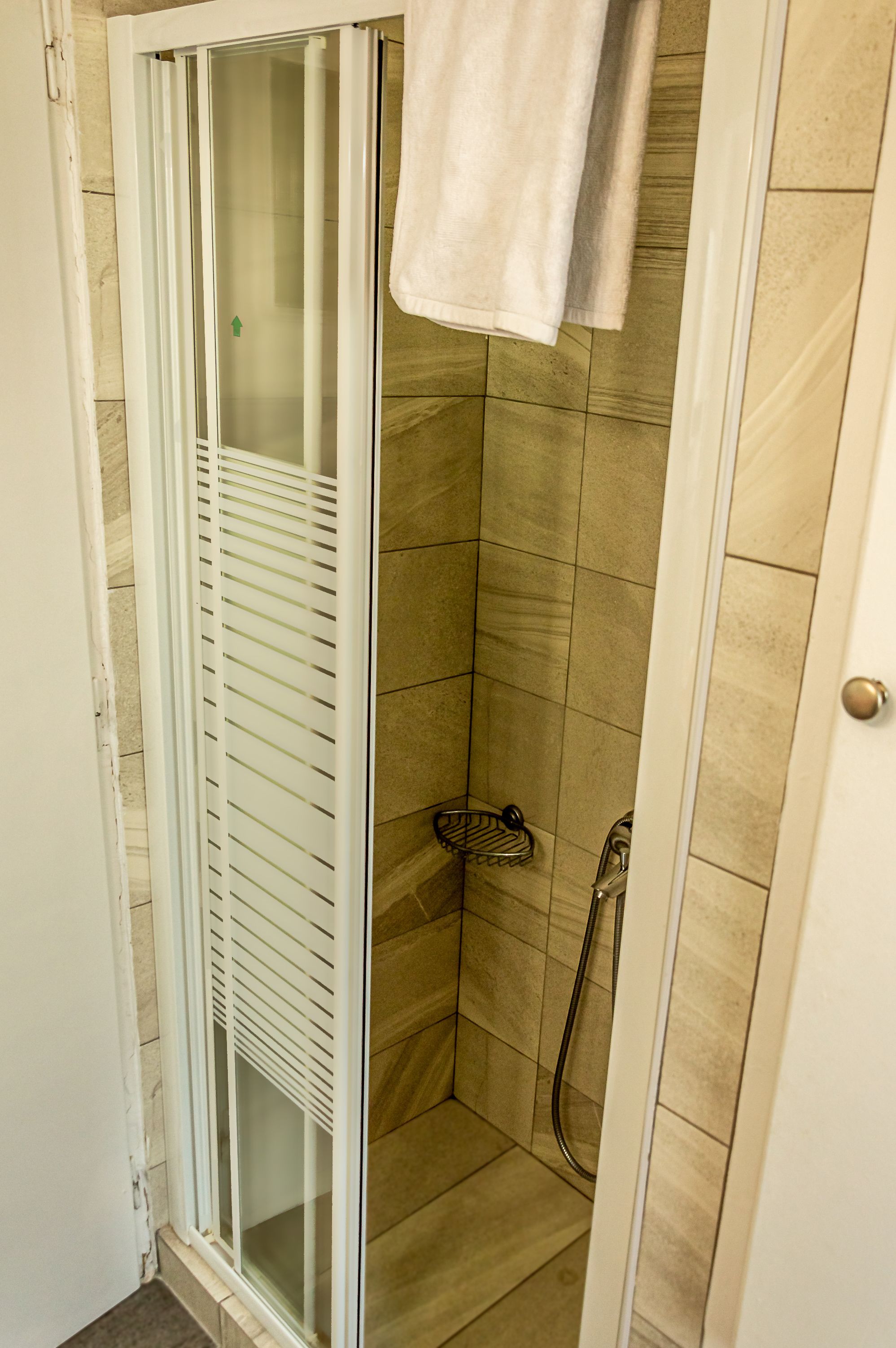 A shower with a glass door, a towel hanging on the wall, and a showerhead.