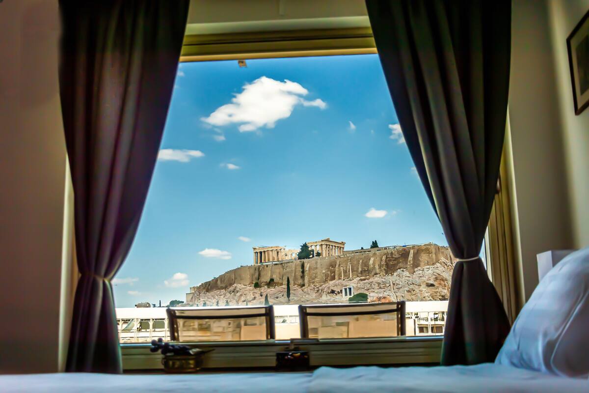 A hotel room with a view of ancient ruins on a hill.