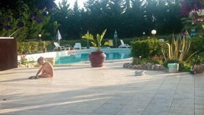 A pool area with a tiled floor, lounge chairs, and a large potted plant. - Seredipa (scopello) fraz Guidaloca - Studio for 2 people (Castellammare del Golfo)