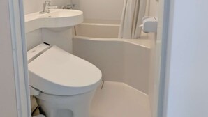 A compact bathroom with a toilet, sink, and shower area.