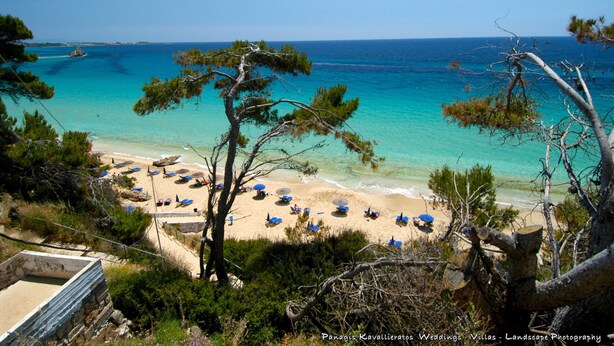 A beach with clear turquoise water, surrounded by trees and a few umbrellas. - ERATO  APARTMENT  IN ARGOSTOLI (Argostoli)